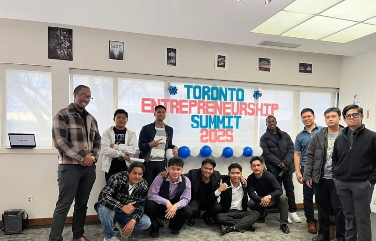 The GT Legacy team posing in the office under a "Toronto Entrepreneurship Summit 2025" banner.
